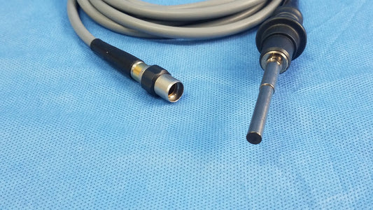 Gray and black Olympus WA03200A S fiber optic light cable with metallic connector coiled on blue surgical drapes
