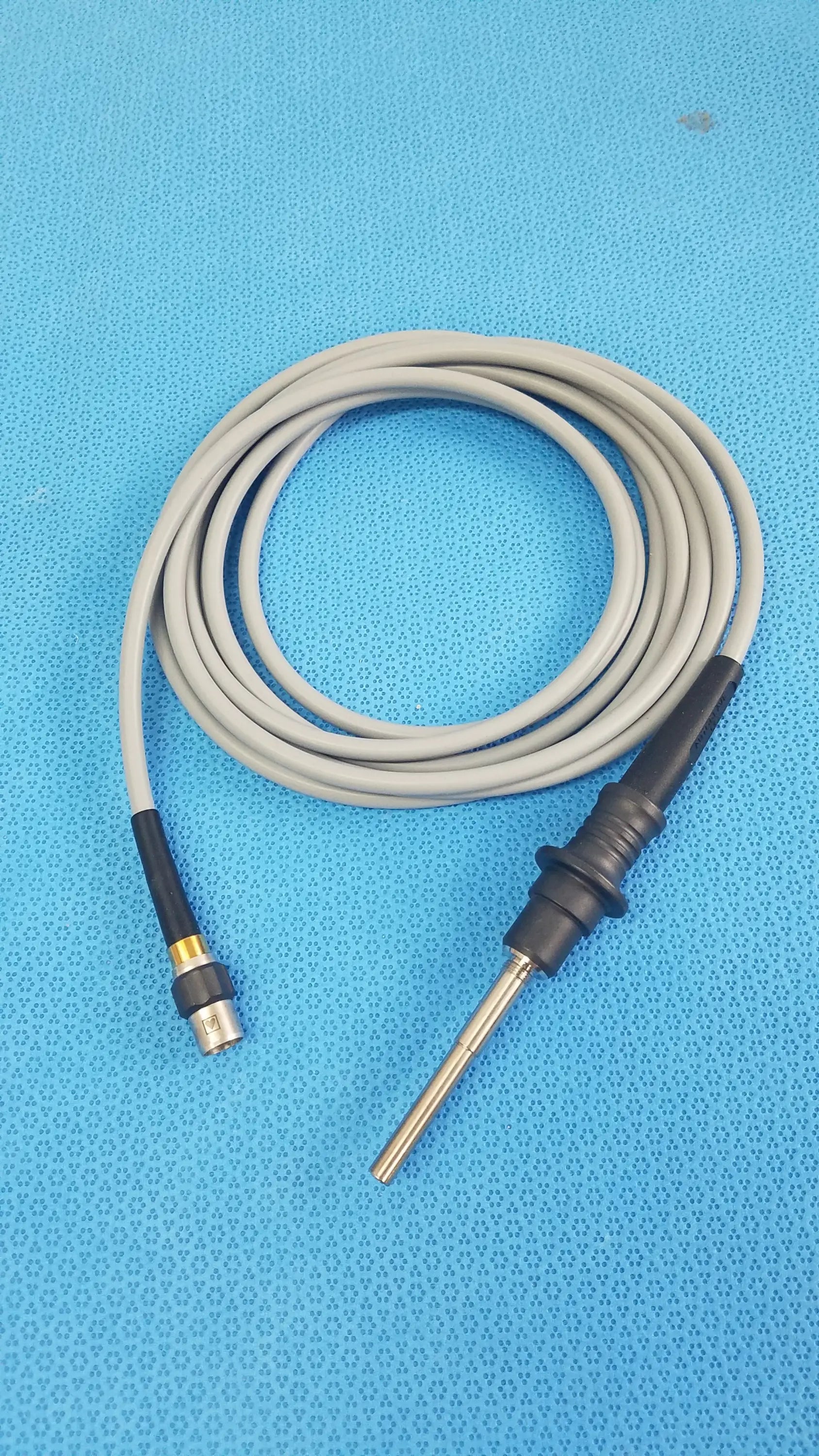 Gray coiled fiber optic light cable with black connectors and metallic probe tip for reuse medical equipment olympus wa03200a