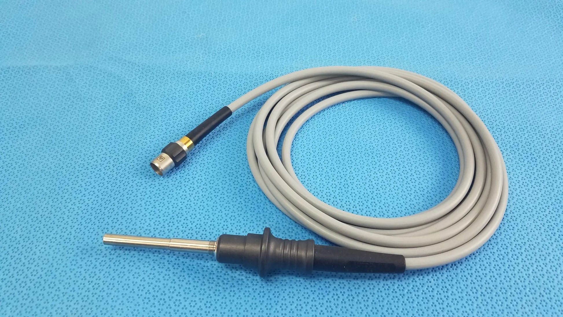Gray coiled olympus wa03200a s fiber optic light cable with black handle, metallic probe tip, and gold connector for medical equipment