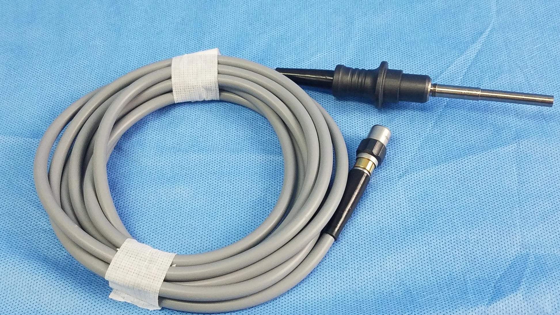 Gray coiled Olympus WA03200A S fiber optic light cable with black and metallic connectors for medical endoscope use