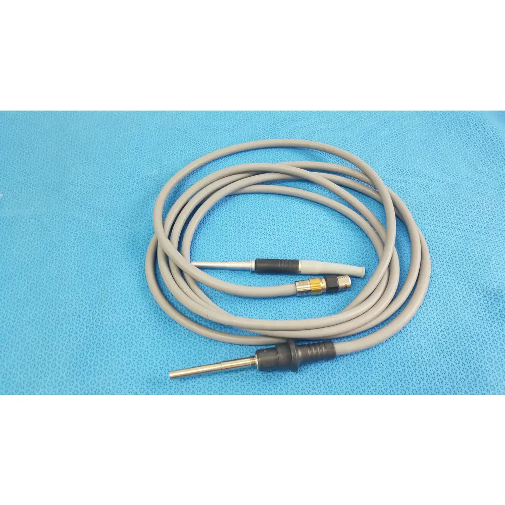 Gray coiled medical equipment cable with black and metallic connectors for olympus wa03300a light guide use