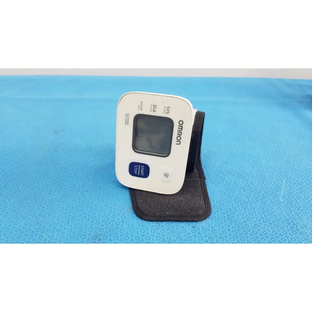 White omron automatic wrist blood pressure monitor with digital display and blue start stop button for accurate readings