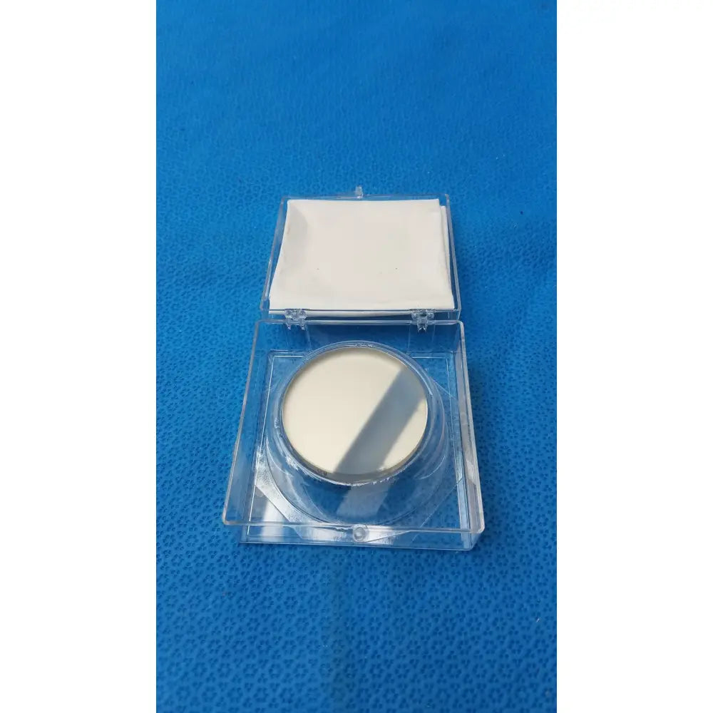 A circular off-white optical container with metallic rim and clear plastic casing by Spawr Industries with mirror