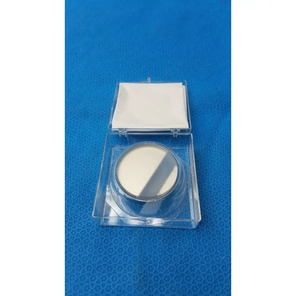 A circular off-white optical container with metallic rim and clear plastic casing by Spawr Industries with mirror
