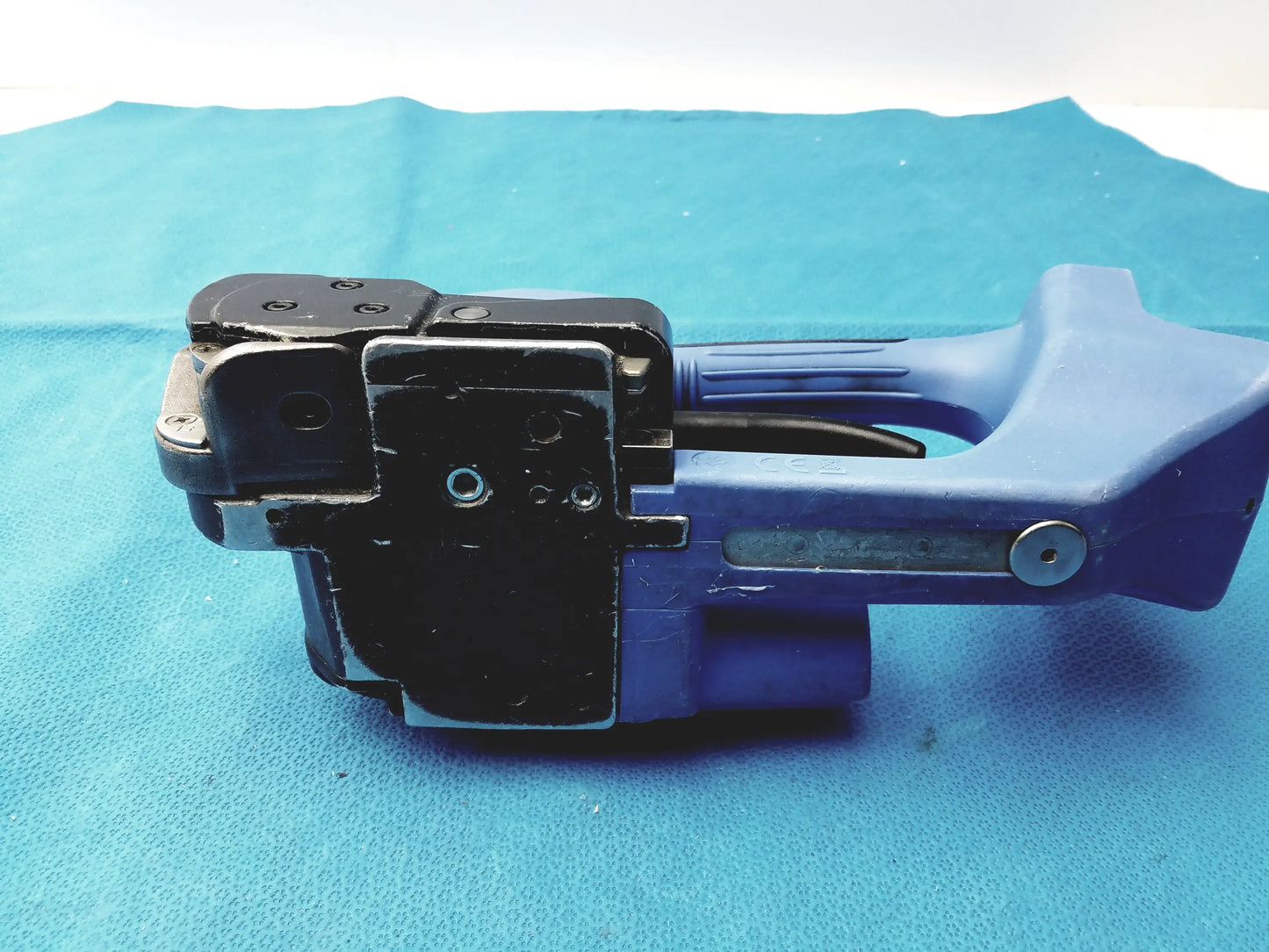 Blue plastic and black metal handheld battery operated cordless label applicator with trigger mechanism for reuse medical equipment