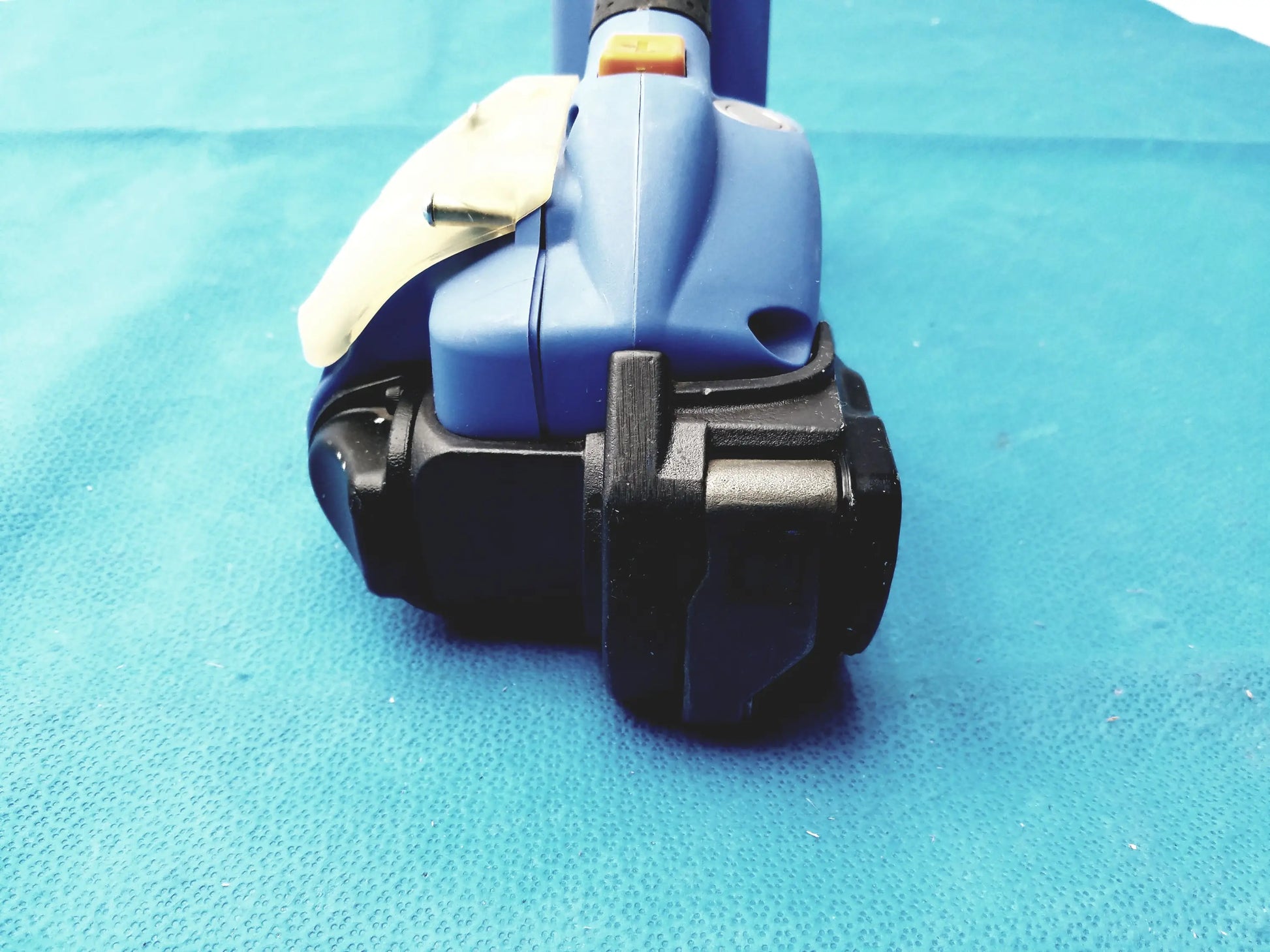 Blue and black handheld battery operated cordless strapping tool with yellow trigger for reuse medical equipment by orgapack