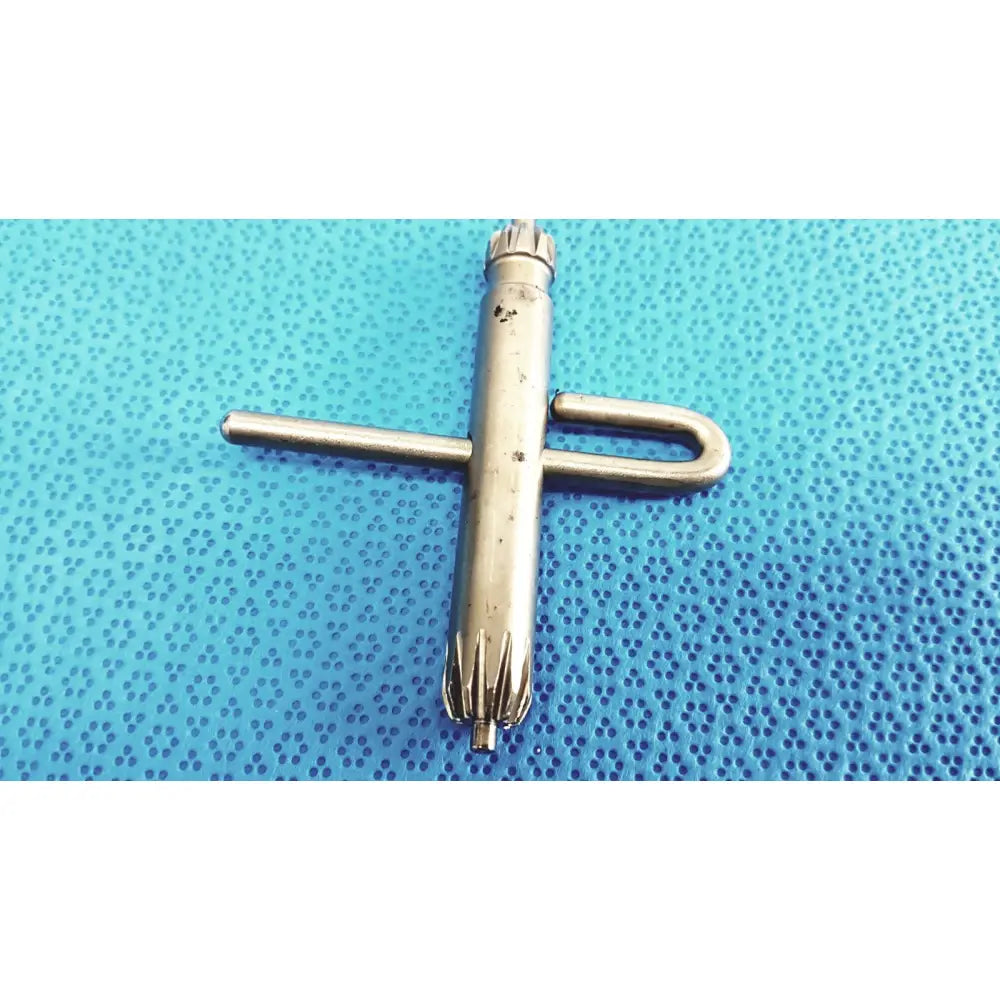 Silver-colored metal orthopedic drill chuck key with cross handle and serrated jaws compatible with 3.8mm and 3.2mm pin holes