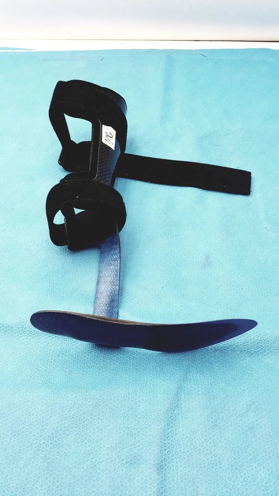 Black orthotic foot drop brace left foot with adjustable straps and curved metal plate for support and stability