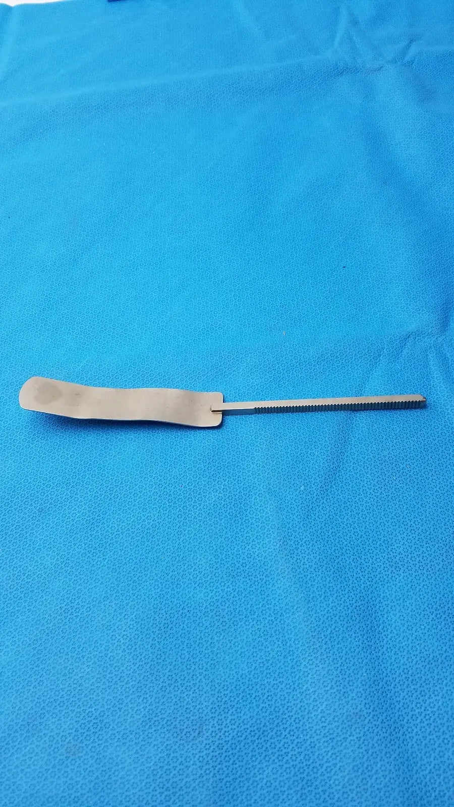 Osteotome stainless steel surgical instrument with a flat rectangular handle and serrated steel surgical blade