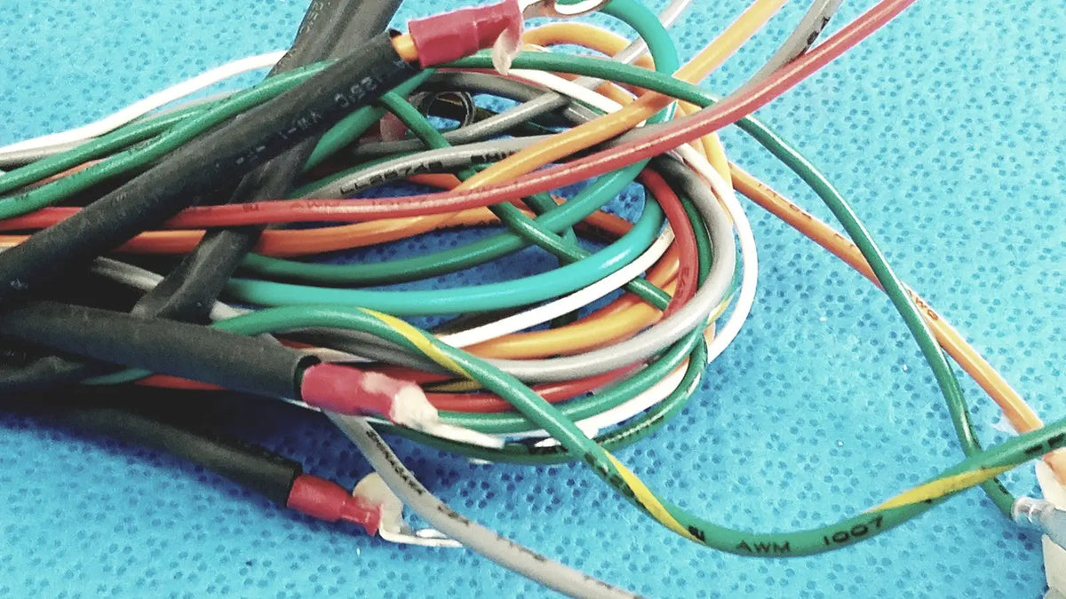 A tangle of multi-colored connectors wire harness cables with black green red white and yellow insulation and red connectors