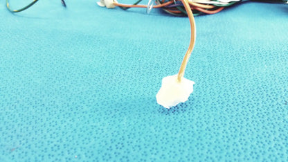 A white irregular foam pad attached to a beige cable in the p10 103 connectors wire harness cable assembly