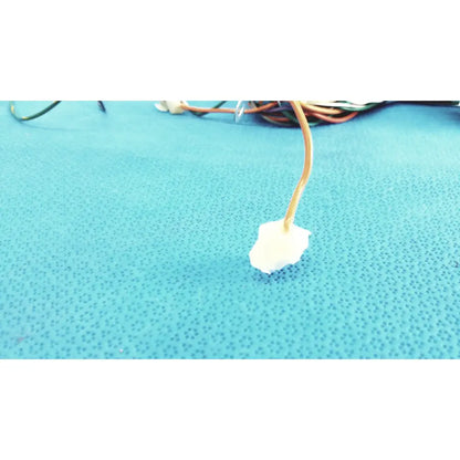 A white irregular foam pad attached to a beige cable in the p10 103 connectors wire harness cable assembly
