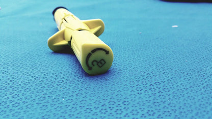 Yellow plastic syringe with black tip and circular logo on barrel from persys medical nio adult simulation kit