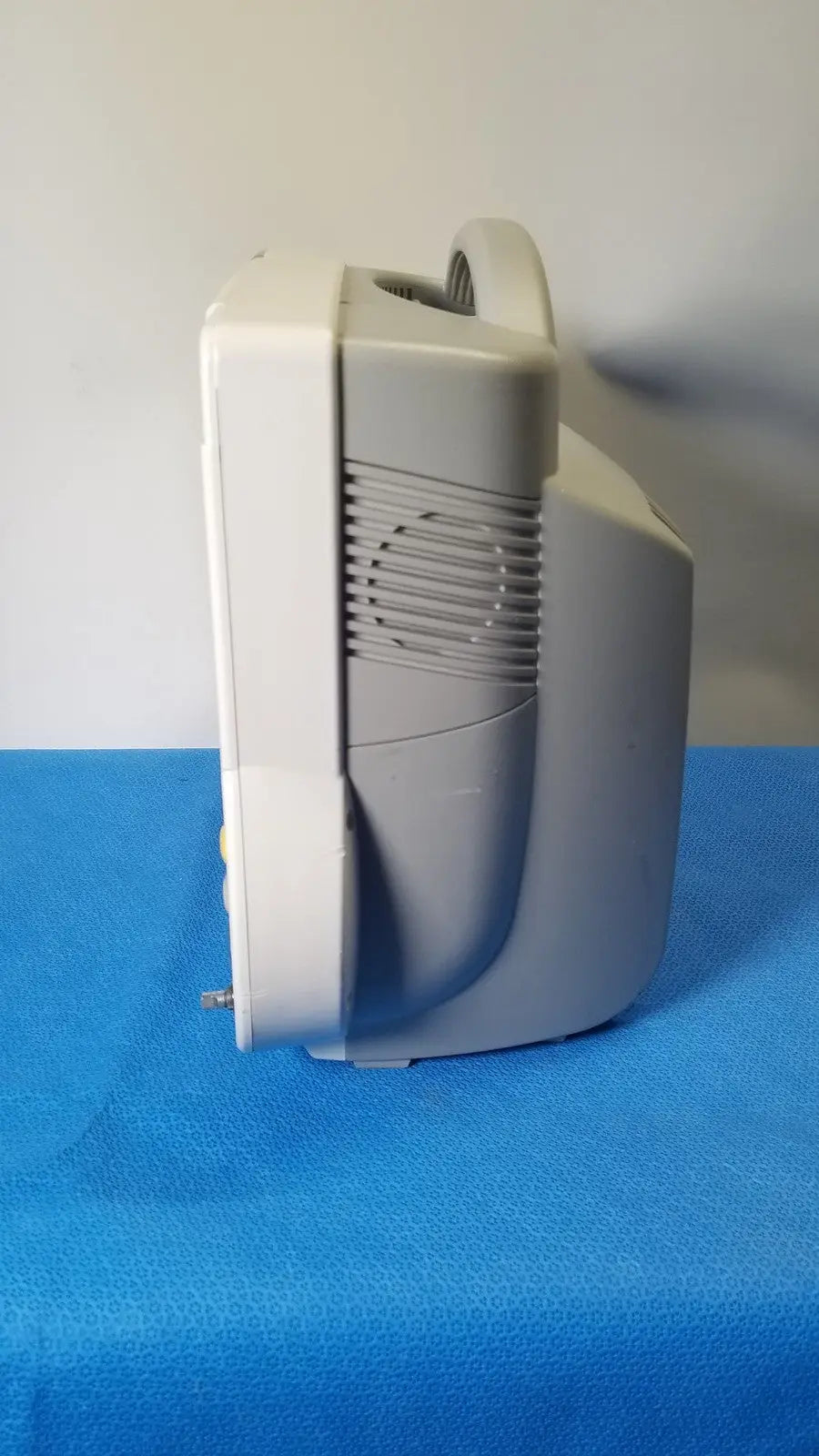 Gray plastic nebulizer with curved handle and vented side panel on the back of philips intellivue m8105a patient monitor