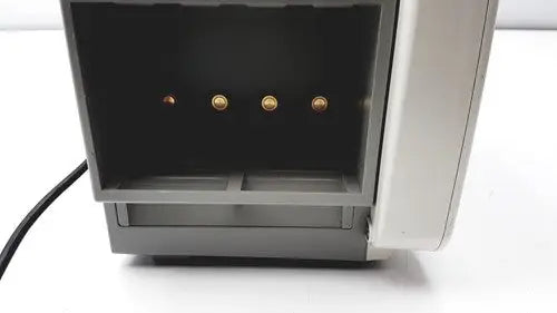 Gray plastic cash register with four gold-colored coin slots shown with philips intellivue mp50 patient monitor A