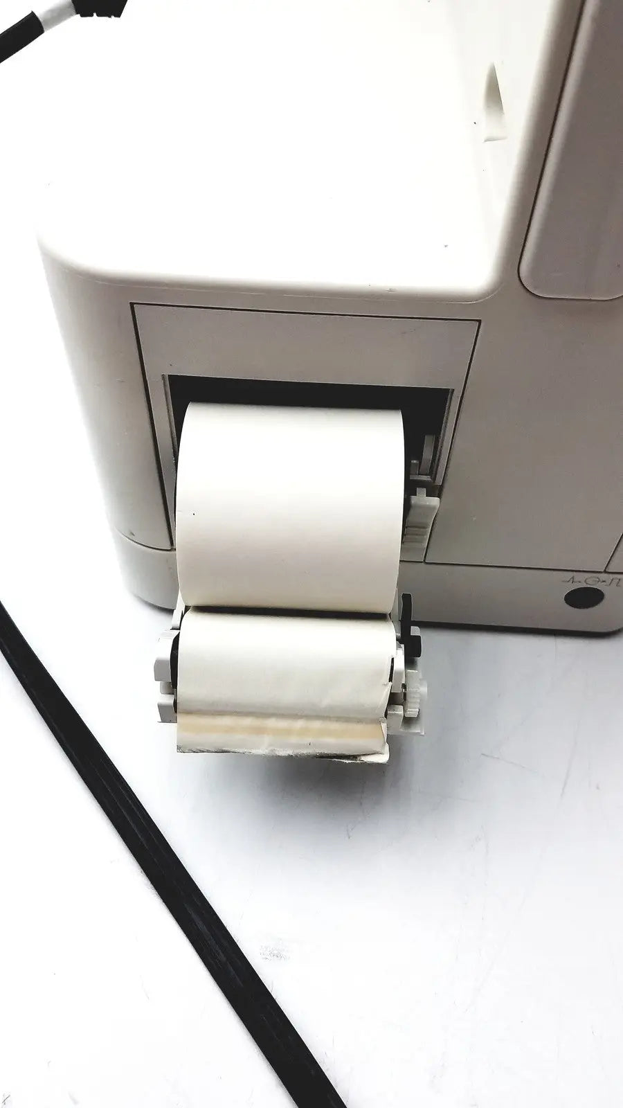 A white paper roll emerging from the printer output tray of a Philips IntelliVue MX400 patient monitor