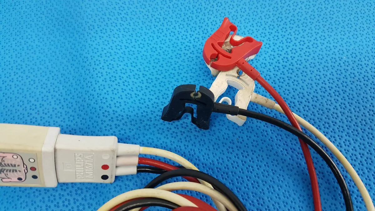 Red and black insulated wires connected to a white philips m1671a ecg leadset with red and black indicator lights