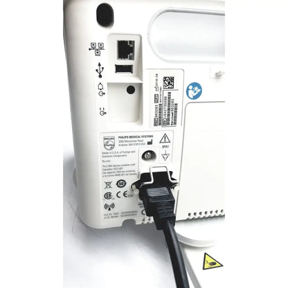 Rear panel of white philips suresigns vs4 vital signs monitor with black power cord plugged in for medical use