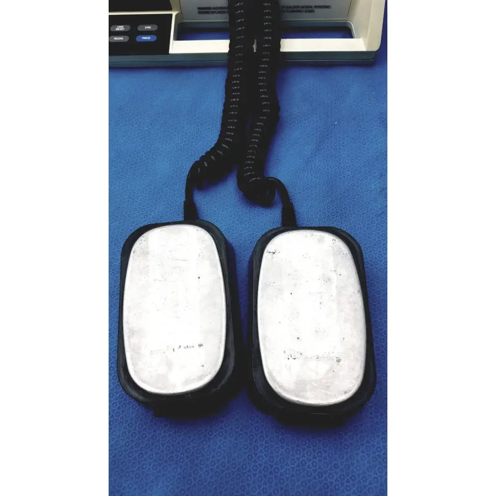 Black rubber-coated foot pedals with silver metallic plates and coiled cord for physio control lifepak 10 cardiac monitor