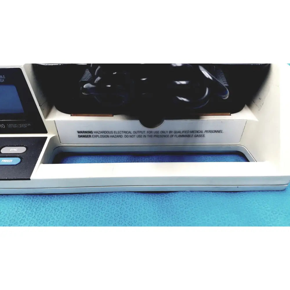 White physio control lifepak 10 cardiac monitor with black control panel blue tray and hazardous electrical output warning label