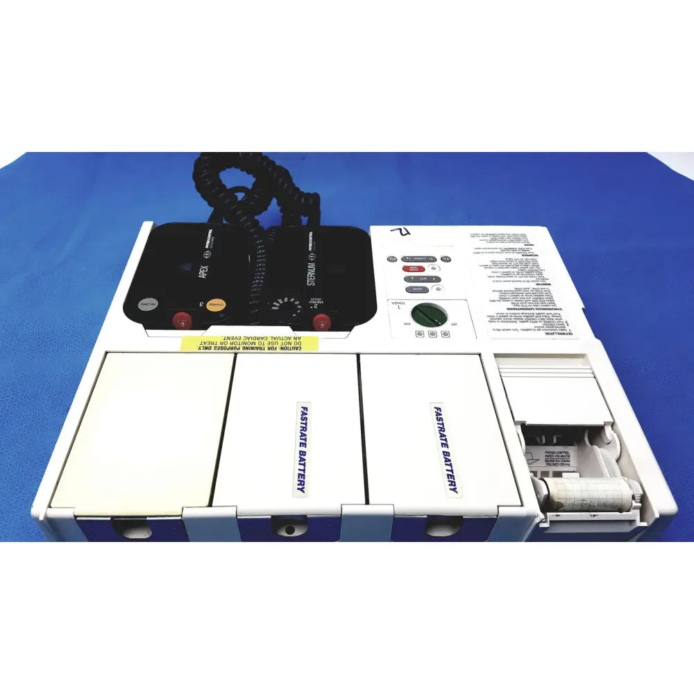 White physio control lifepak 10 cardiac monitor with black control panel and two labeled battery compartments visible