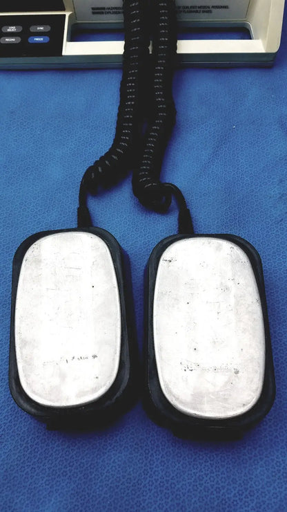 Black rubber-coated foot pedals with silver metallic plates and coiled cord for physio control lifepak 10 cardiac monitor