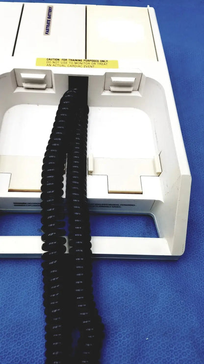 Black coiled cable extending from a white physio control lifepak 10 cardiac monitor showing the back side connection