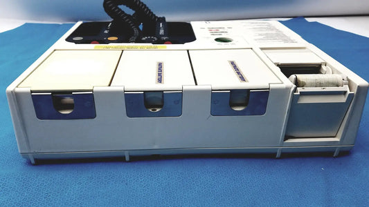 White and blue physio control lifepak 10 cardiac monitor with three labeled compartments and open paper roll compartment