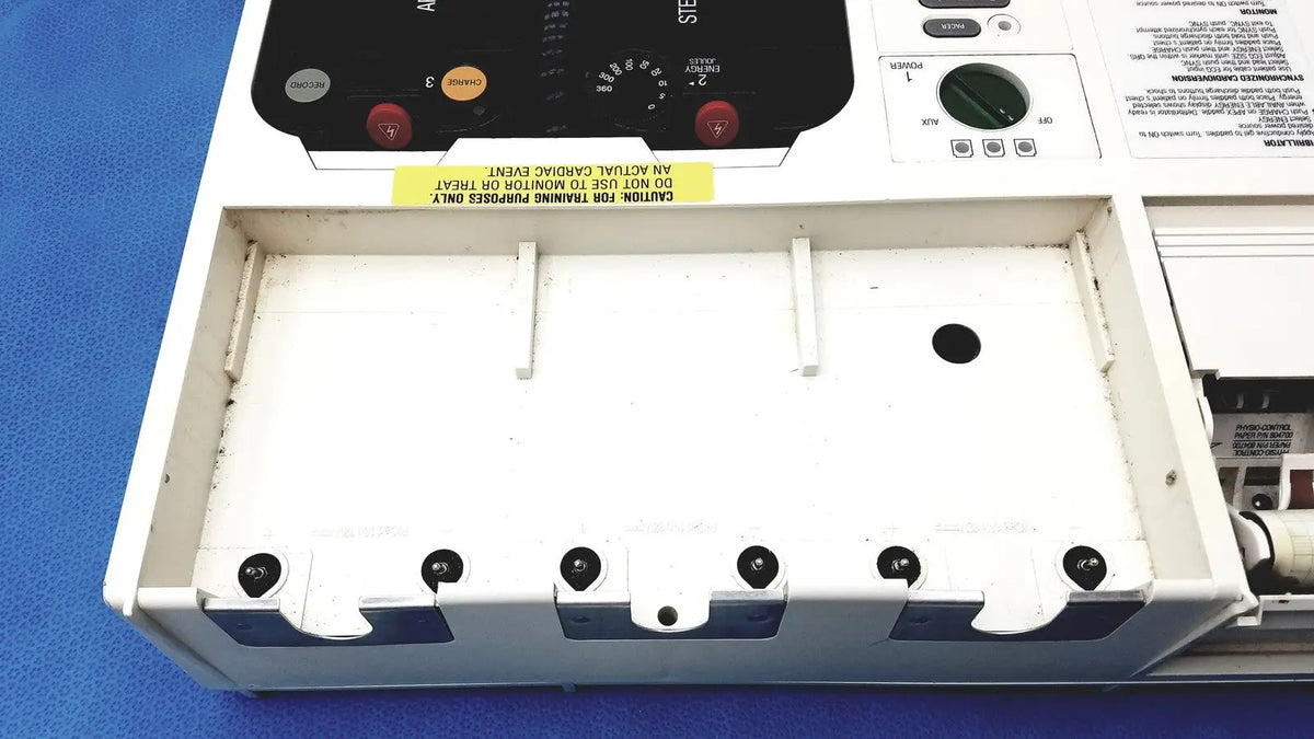 White plastic medical training mannequin with black control panel and warning label for physio control lifepak 10 cardiac monitor
