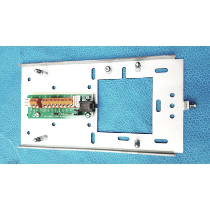 White metal mounting plate with green circuit board and orange terminal block on planmeca intra x-ray control pad back side