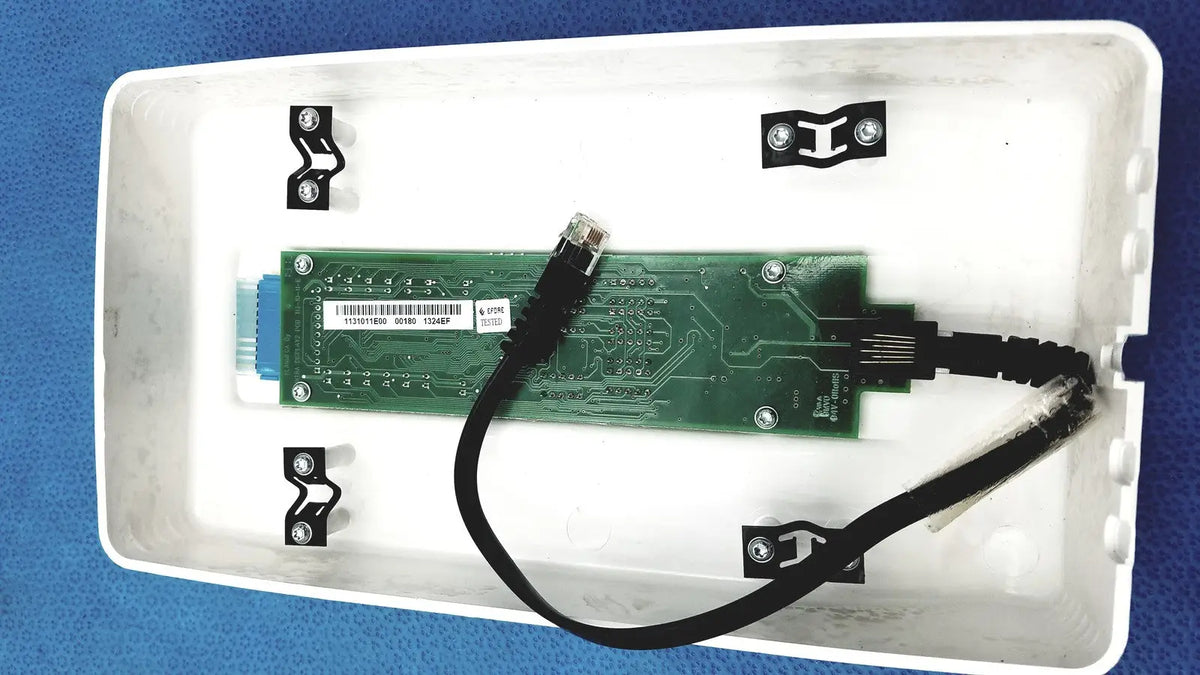 Green circuit board with black cable and silver screws inside white plastic enclosure of planmeca intra x-ray control pad back side