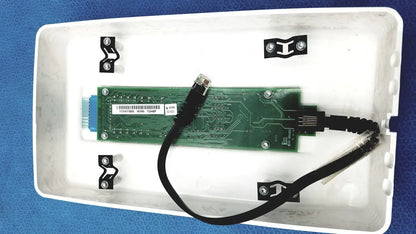 Green circuit board with black cable and silver screws inside white plastic enclosure of planmeca intra x-ray control pad back side