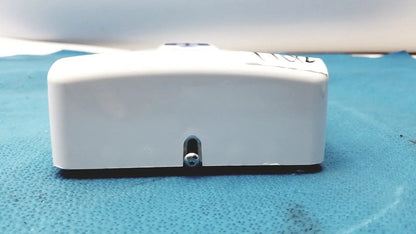White rectangular plastic planmeca intra x-ray control pad with small silver screw and black base visible from back side