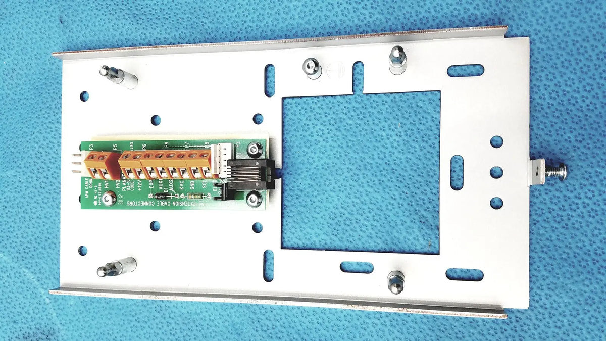 White metal mounting plate with green circuit board and orange terminal block on planmeca intra x-ray control pad back side