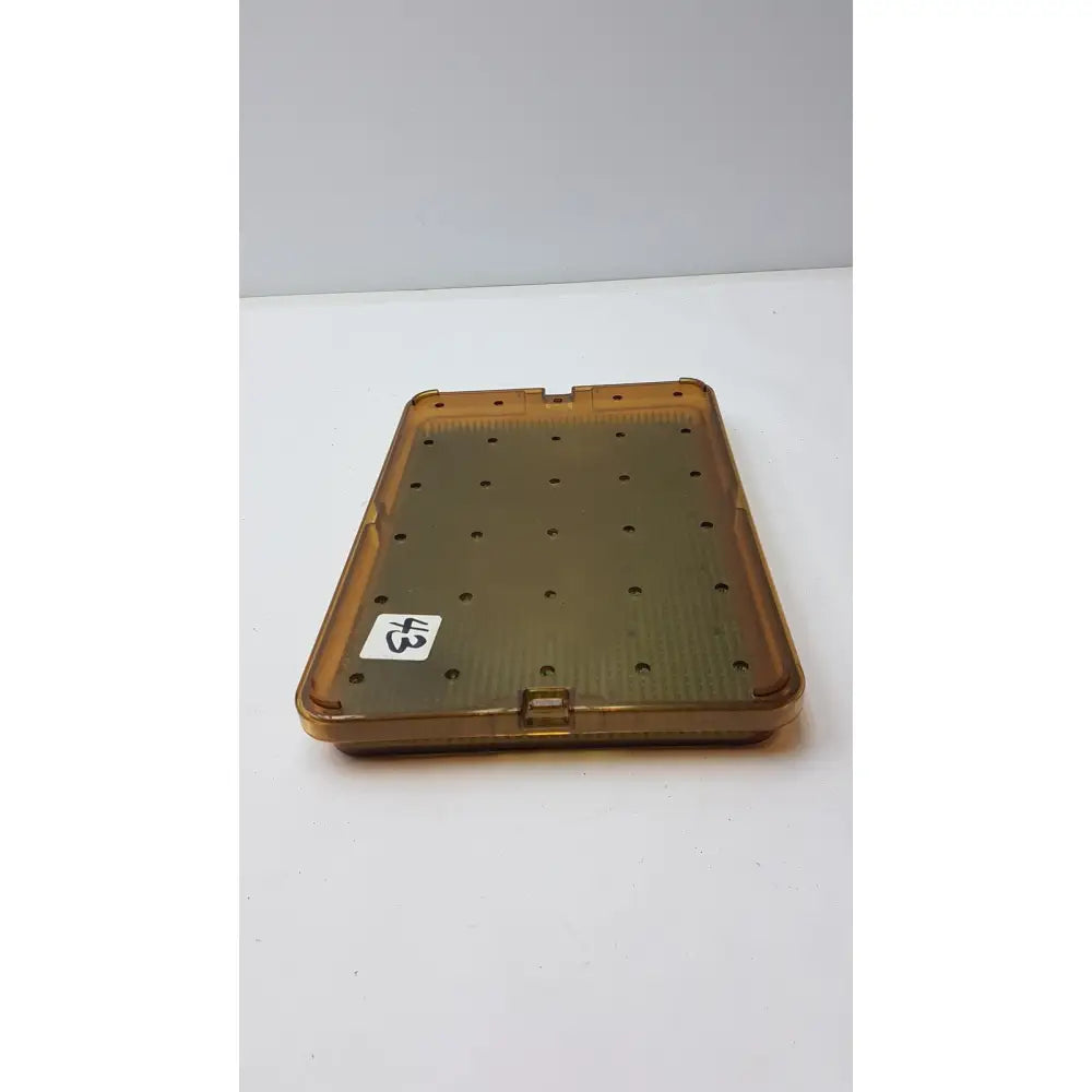Transparent amber plastic sterilization tray with silicone finger mat and circular holes for organized instrument storage
