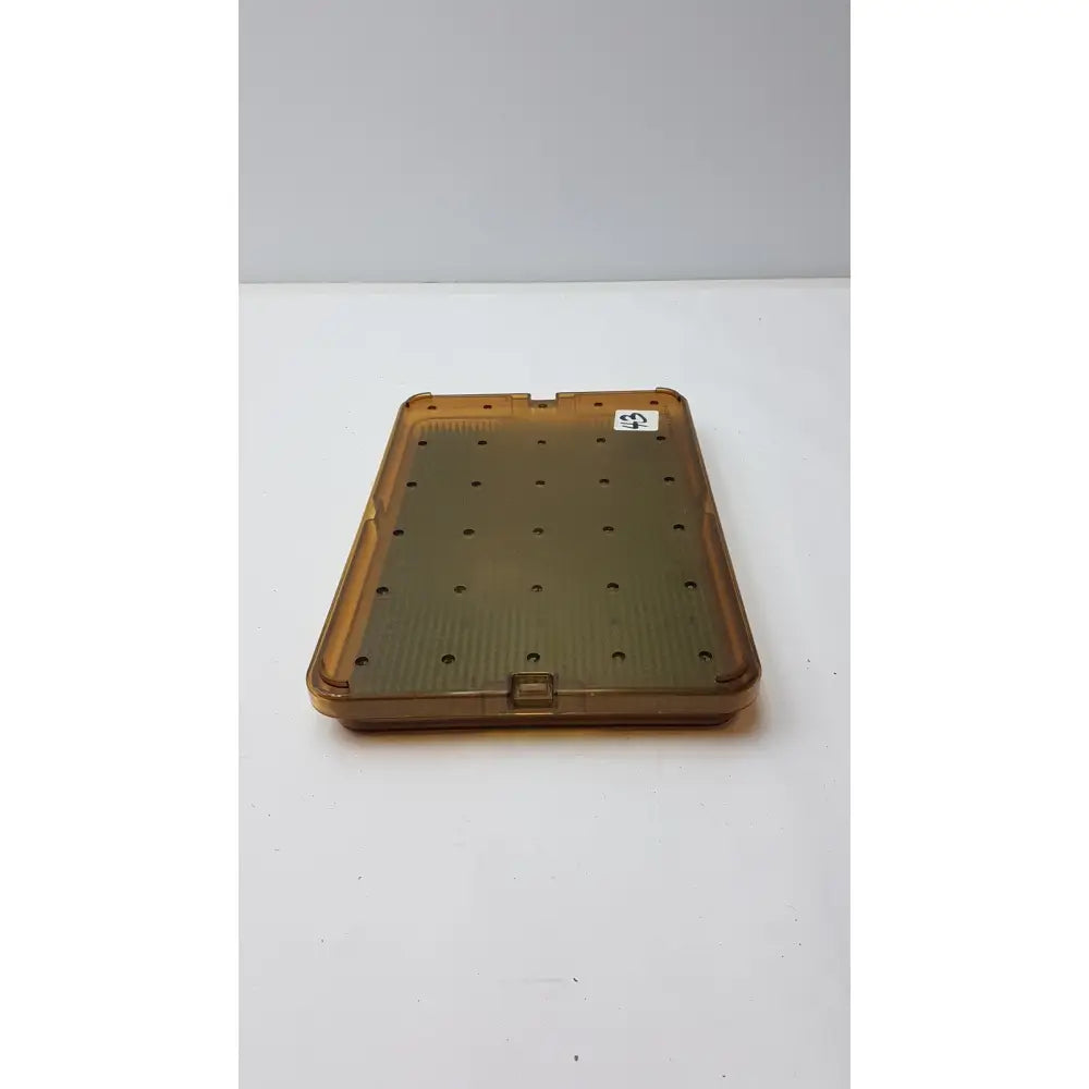 Transparent amber plastic sterilization tray with silicone finger mat featuring evenly spaced circular holes