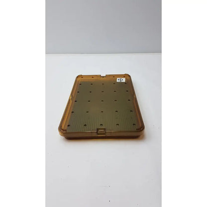 Transparent amber plastic sterilization tray with silicone finger mat featuring evenly spaced circular holes