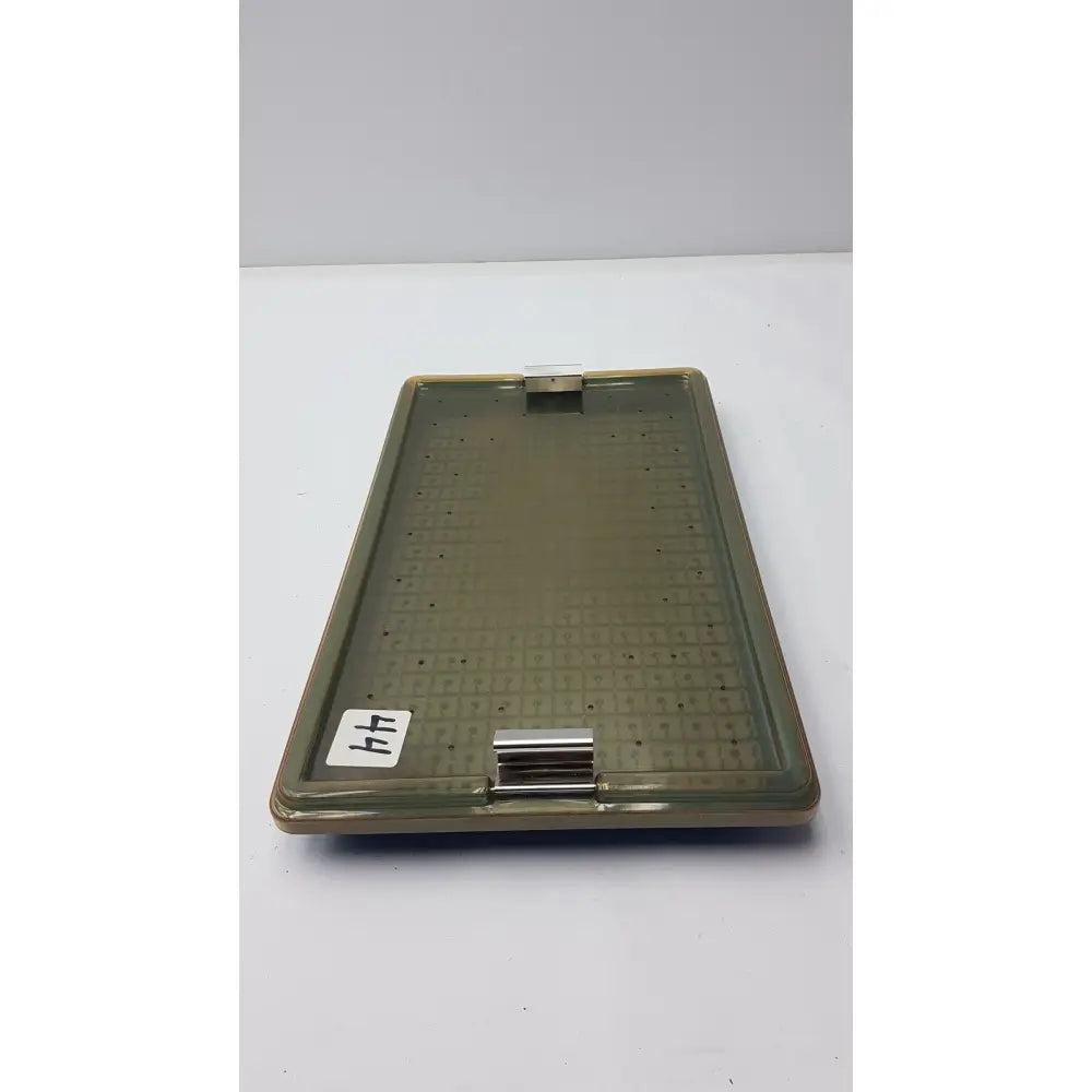 Olive-green plastic sterilization tray with metallic clasp and perforated surface featuring silicone finger mat