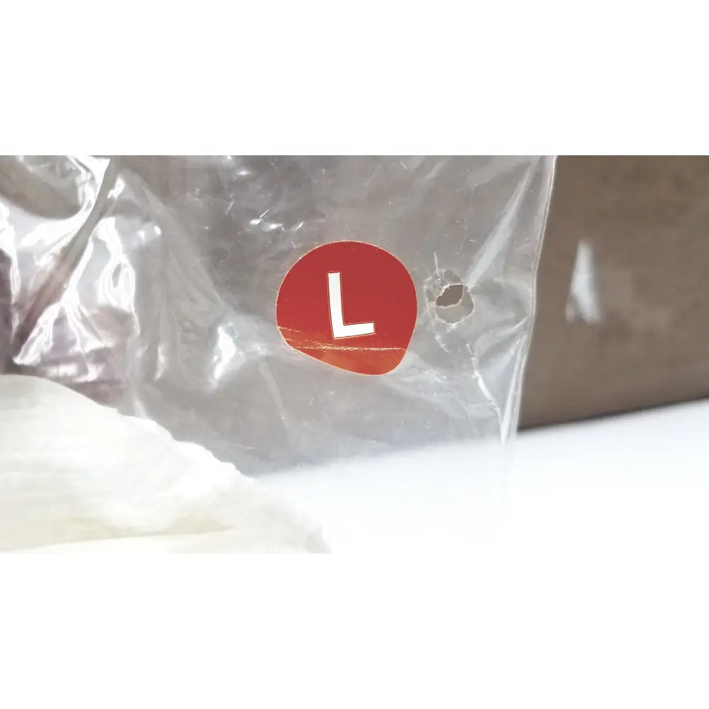 A red circular label with a white l on transparent plastic packaging for posey quick dry slippers slip rubber soles size l