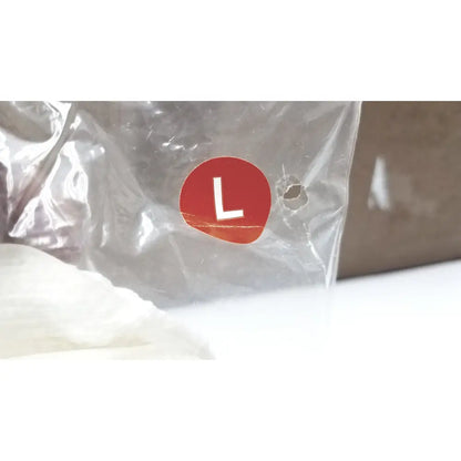 A red circular label with a white l on transparent plastic packaging for posey quick dry slippers slip rubber soles size l