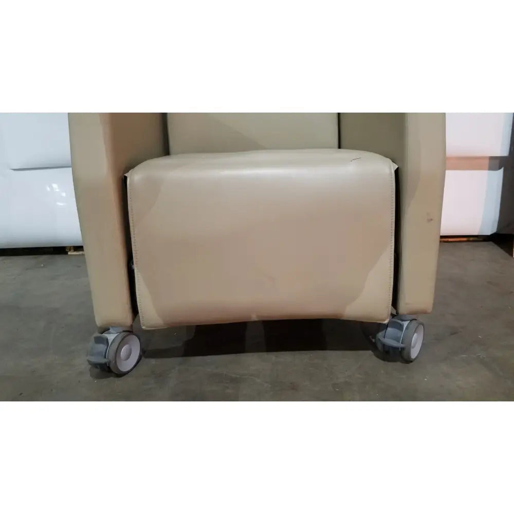 Beige leather power recovery recliner with caster wheels and hand control for enhanced recovery comfort