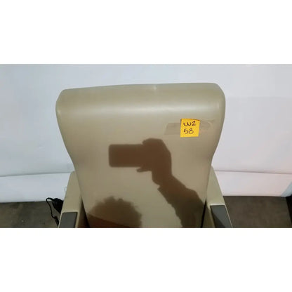 Beige upholstered power recovery recliner with hand control and yellow sticky note on the headrest
