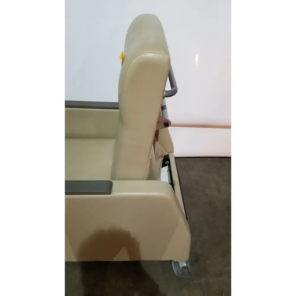 Beige upholstered power recovery recliner with padded backrest armrests and gray metal frame featuring hand control