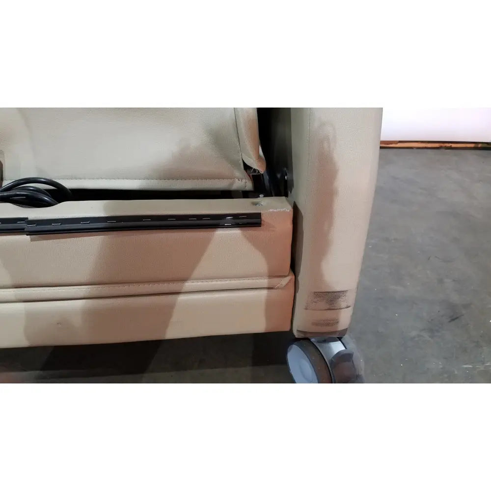 Beige leather power recovery recliner with black trim and caster wheels featuring hand control for easy adjustment