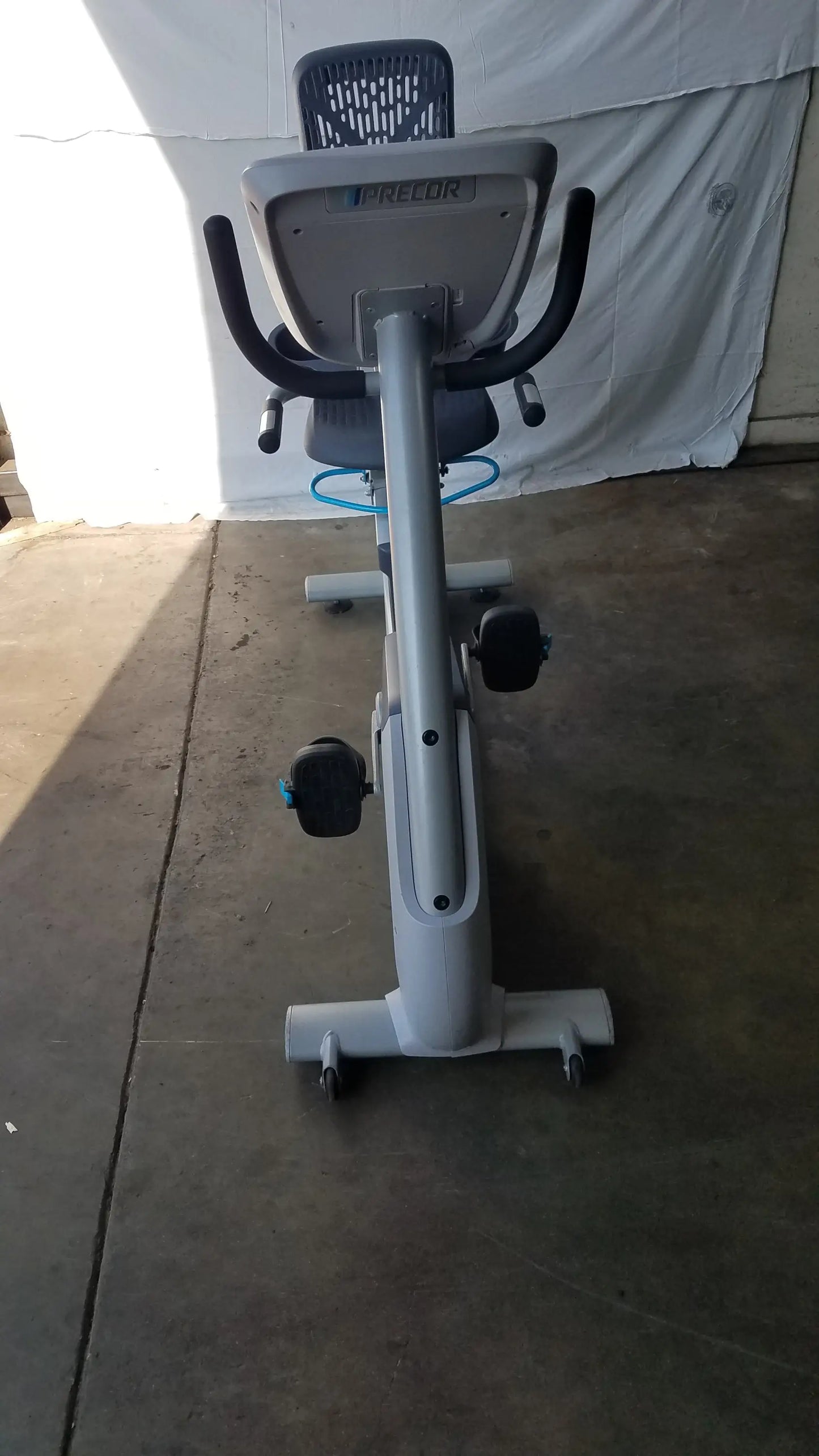 Gray precor recumbent exercise bike with sleek metallic frame, black seat and handlebars, blue accent tubing, and precor console