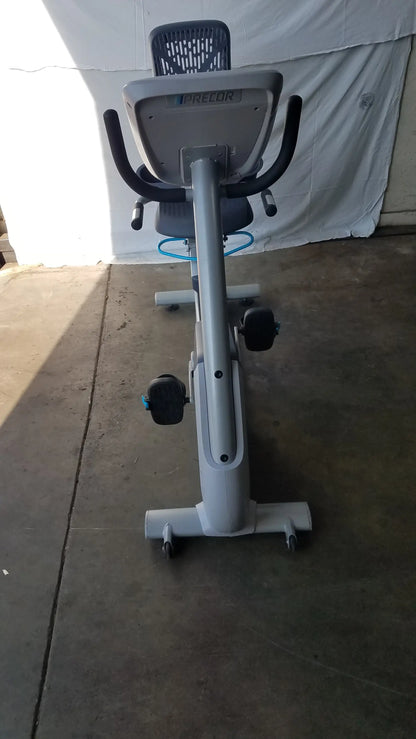Gray precor recumbent exercise bike with sleek metallic frame, black seat and handlebars, blue accent tubing, and precor console