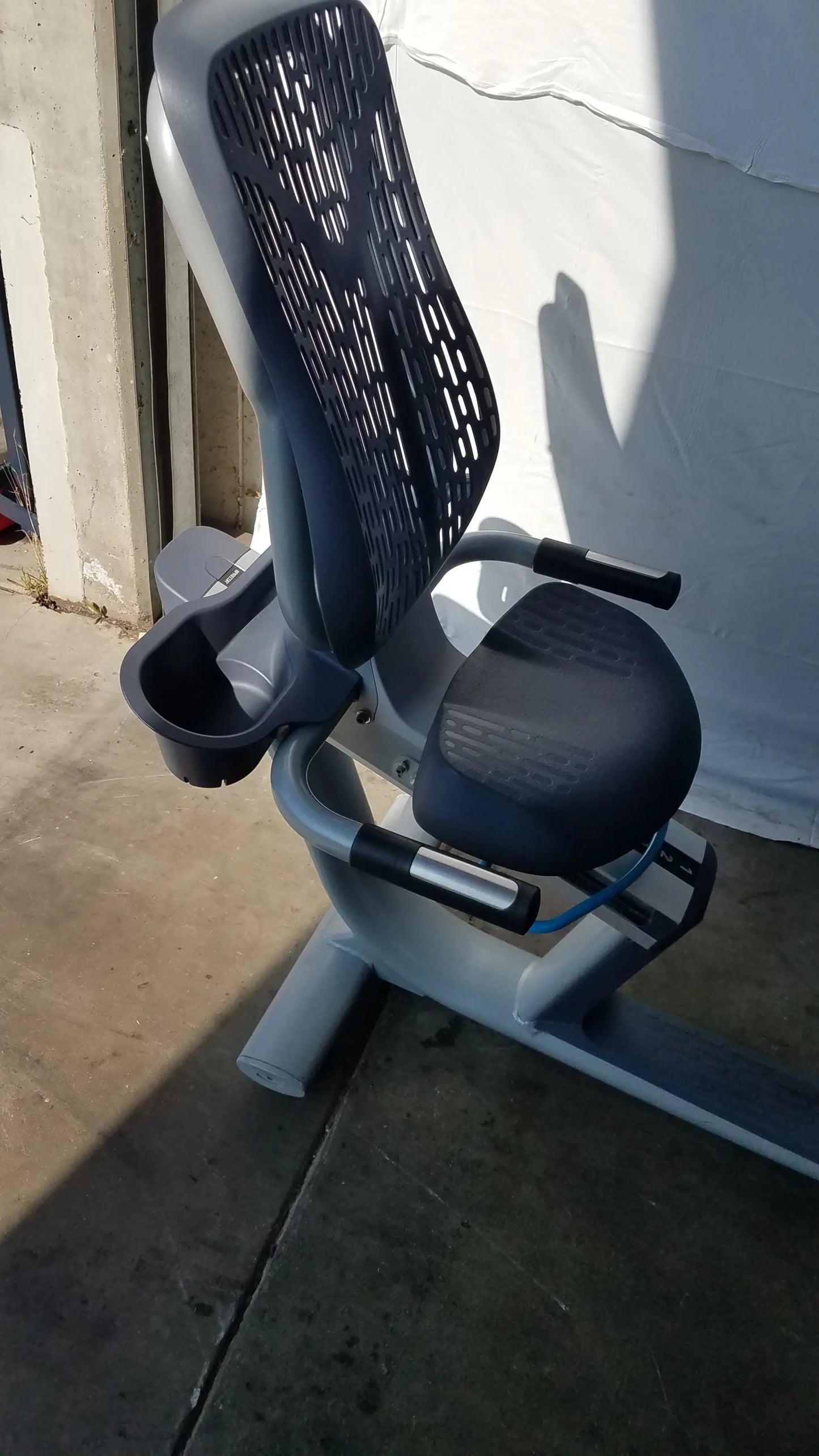 Gray and black recumbent exercise bike with precor console, mesh backrest, padded seat, and integrated cup holder