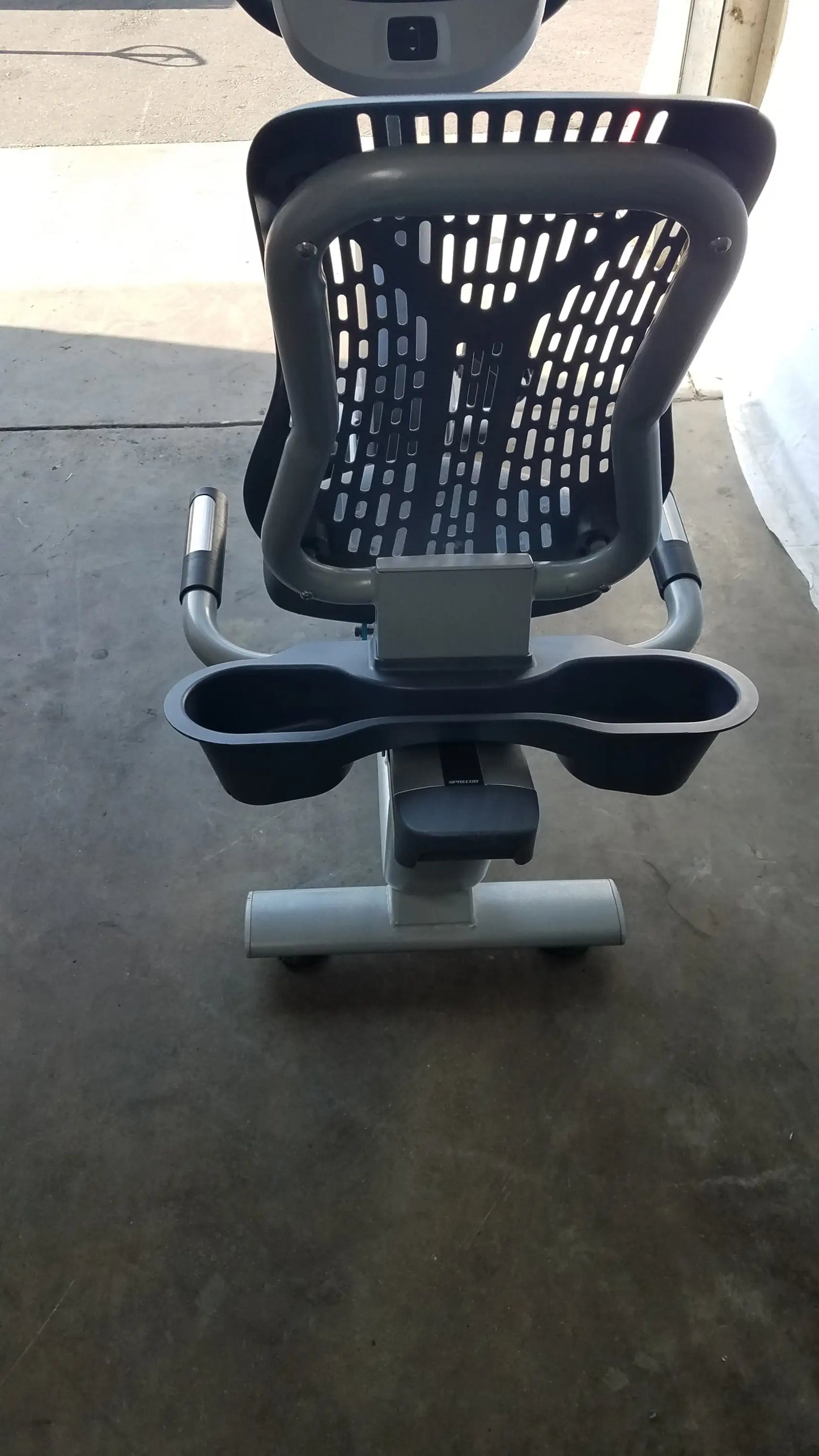 Gray and black precor recumbent exercise bike with perforated backrest adjustable handlebars and precor console cup holders
