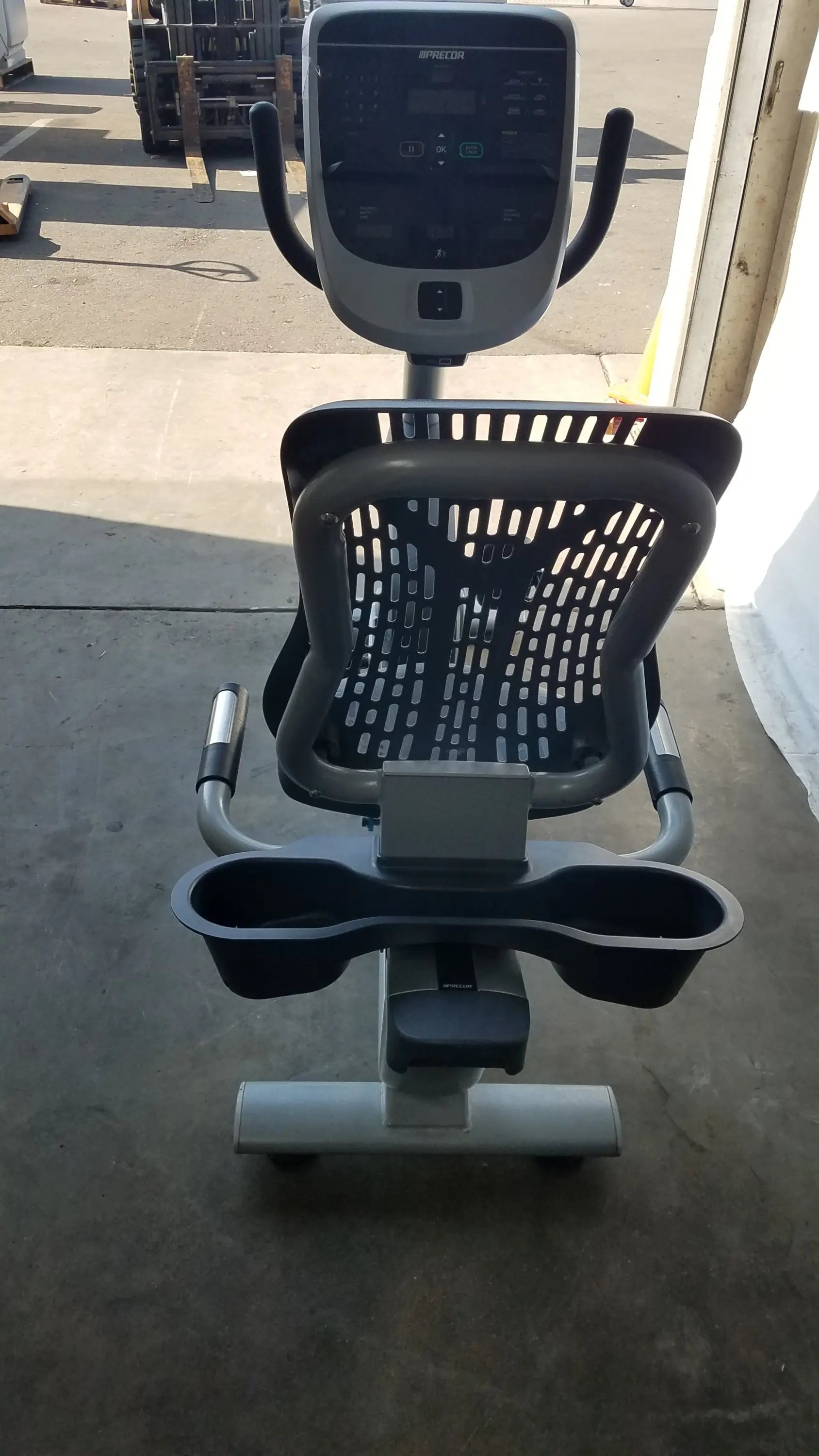 Gray and black recumbent exercise bike with precor console digital display perforated backrest and cup holders