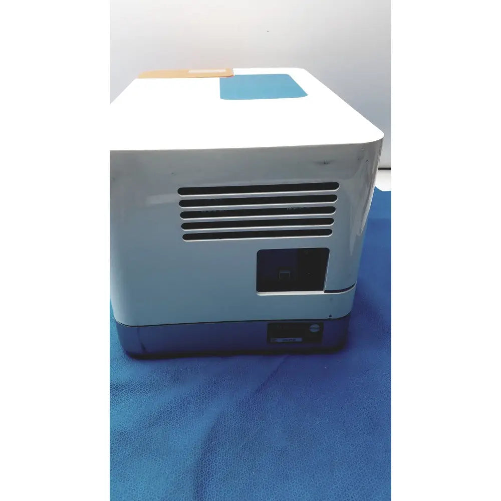 White and blue proteinsimple wes analyzer printer showing rectangular ventilation grille on the side